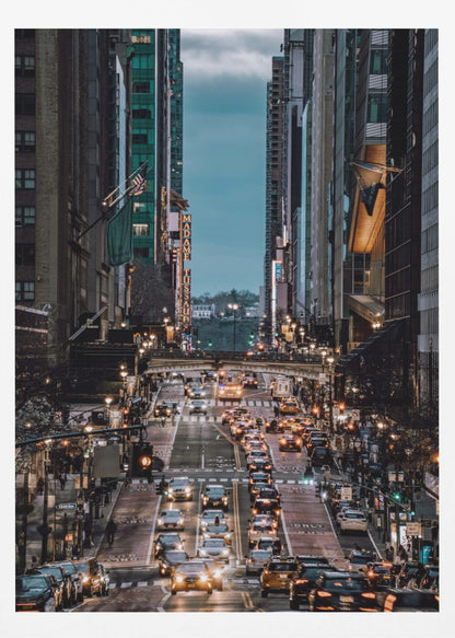 A high-angle, vertical photograph looking down a bustling New York City street at dusk, framed by towering skyscrapers. The street below is packed with cars, their headlights creating a warm golden glow, contrasting with the cool, dark blue tones of the twilight sky and buildings. Poster