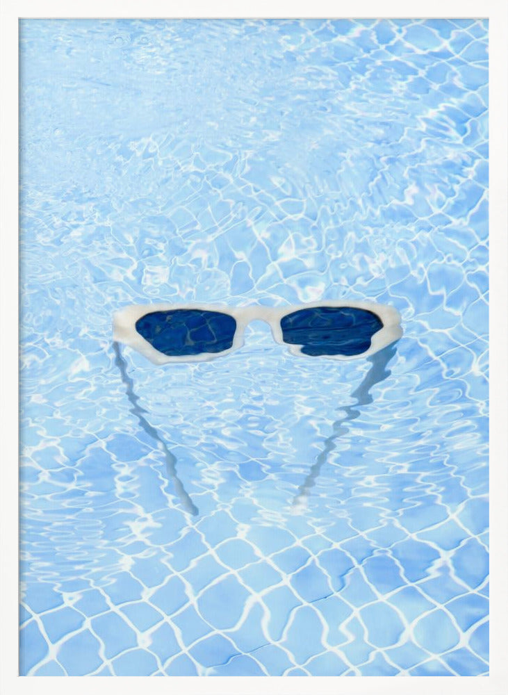 A pair of white-framed sunglasses with dark lenses floats on the surface of a bright blue swimming pool. The rippling water distorts the view of the tiled pool floor, and the sunglasses cast a faint shadow underneath. Print