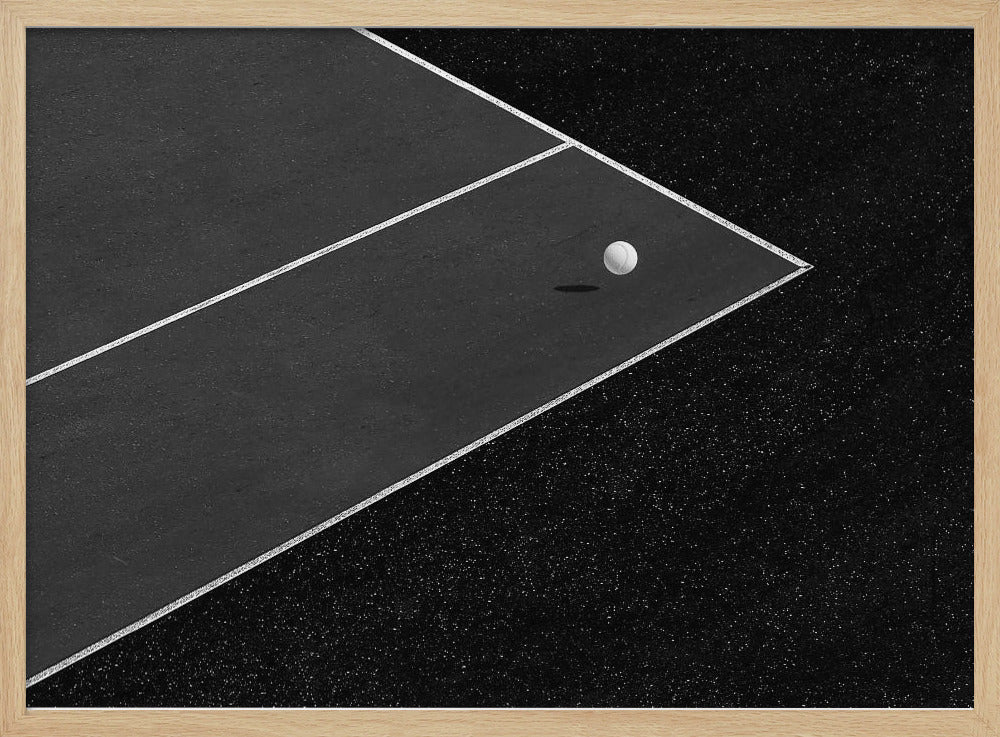 A minimalist black and white overhead photograph of a white ball resting in the corner of a dark tennis or paddle court. The composition focuses on the strong geometric angles created by the white boundary lines against the dark, textured asphalt, all within a silver frame. Artwork