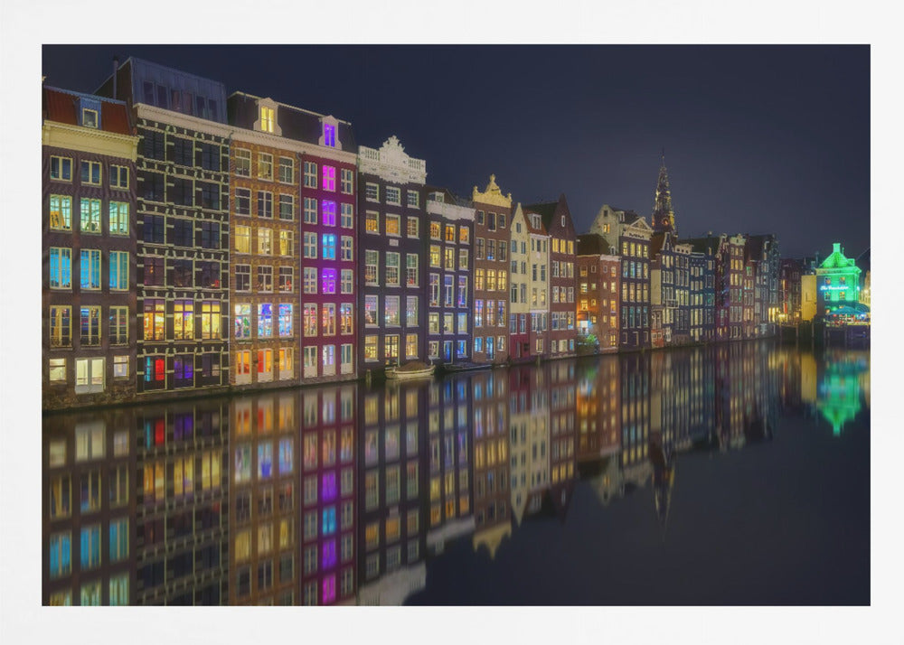 A vibrant nighttime photograph of colorful canal houses in Amsterdam, with their glowing lights beautifully reflected in the still water of the canal below, all framed in silver. Print