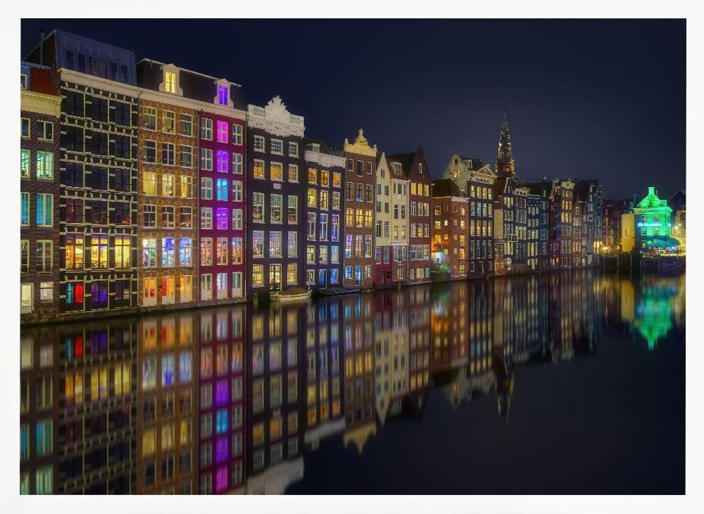 A vibrant nighttime photograph of colorful canal houses in Amsterdam, with their glowing lights beautifully reflected in the still water of the canal below, all framed in silver. Print