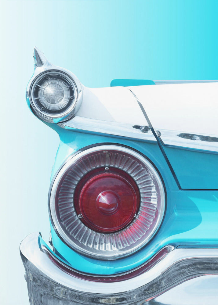 A close-up, framed photograph of the tail fin of a vintage turquoise and white car. The focus is on the large, round, red taillight and the smaller chrome-encased light on the fin, set against a solid light blue background. Poster