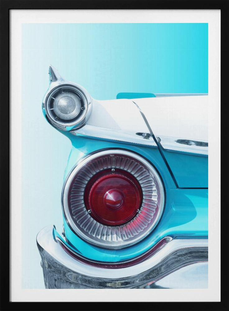 A close-up, framed photograph of the tail fin of a vintage turquoise and white car. The focus is on the large, round, red taillight and the smaller chrome-encased light on the fin, set against a solid light blue background. Poster
