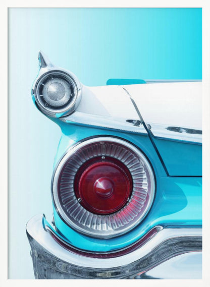 A close-up, framed photograph of the tail fin of a vintage turquoise and white car. The focus is on the large, round, red taillight and the smaller chrome-encased light on the fin, set against a solid light blue background. Poster