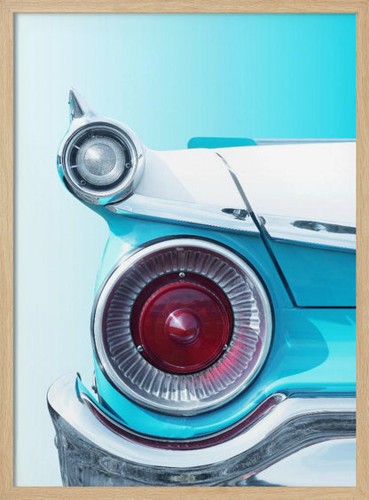 A close-up, framed photograph of the tail fin of a vintage turquoise and white car. The focus is on the large, round, red taillight and the smaller chrome-encased light on the fin, set against a solid light blue background. Poster