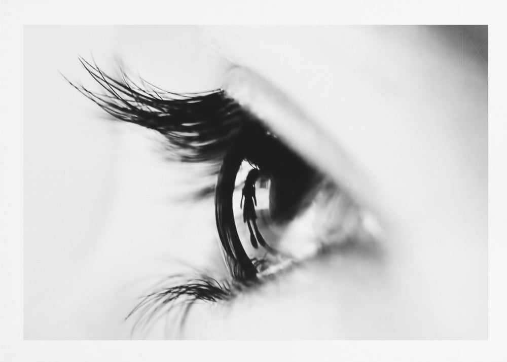 A dramatic black and white macro photograph of a human eye in profile, with a surreal reflection of a person's silhouette visible in the pupil. Print