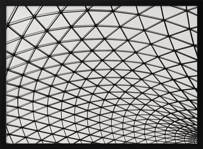 A framed, black and white photograph of a modern architectural dome ceiling. The image is a close-up, looking up at the intricate metal framework that creates a repeating pattern of triangles against the bright glass panels. Poster