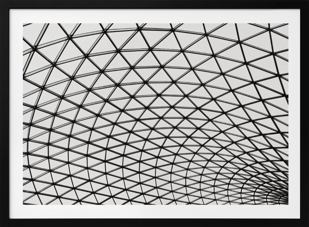 A framed, black and white photograph of a modern architectural dome ceiling. The image is a close-up, looking up at the intricate metal framework that creates a repeating pattern of triangles against the bright glass panels. Poster