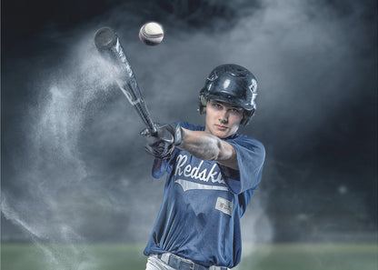 A dramatic, framed portrait of a young baseball player in a blue jersey and helmet, captured in the moment of hitting a baseball, with a cloud of dust exploding from the bat against a dark, smoky background. Poster
