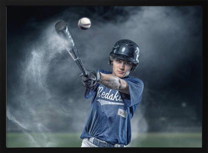 A dramatic, framed portrait of a young baseball player in a blue jersey and helmet, captured in the moment of hitting a baseball, with a cloud of dust exploding from the bat against a dark, smoky background. Poster