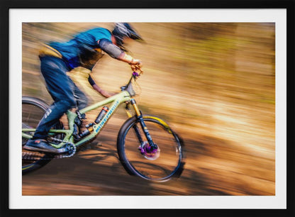 An action shot of a mountain biker in full gear speeding down a dirt trail, captured with a motion blur effect that streaks the brown and green background, conveying a sense of intense speed. Poster