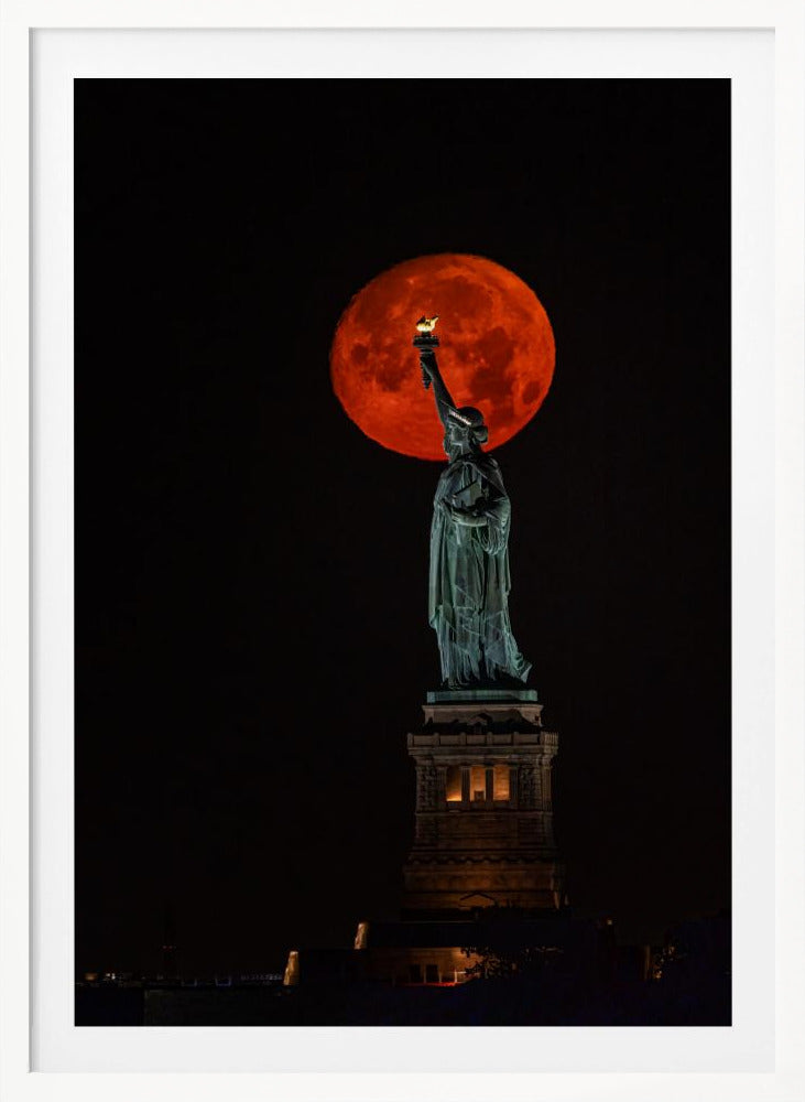 A striking night photograph of the Statue of Liberty perfectly silhouetted against a giant, vibrant red supermoon, which appears to be held aloft by the statue's torch against a deep black sky. Artwork