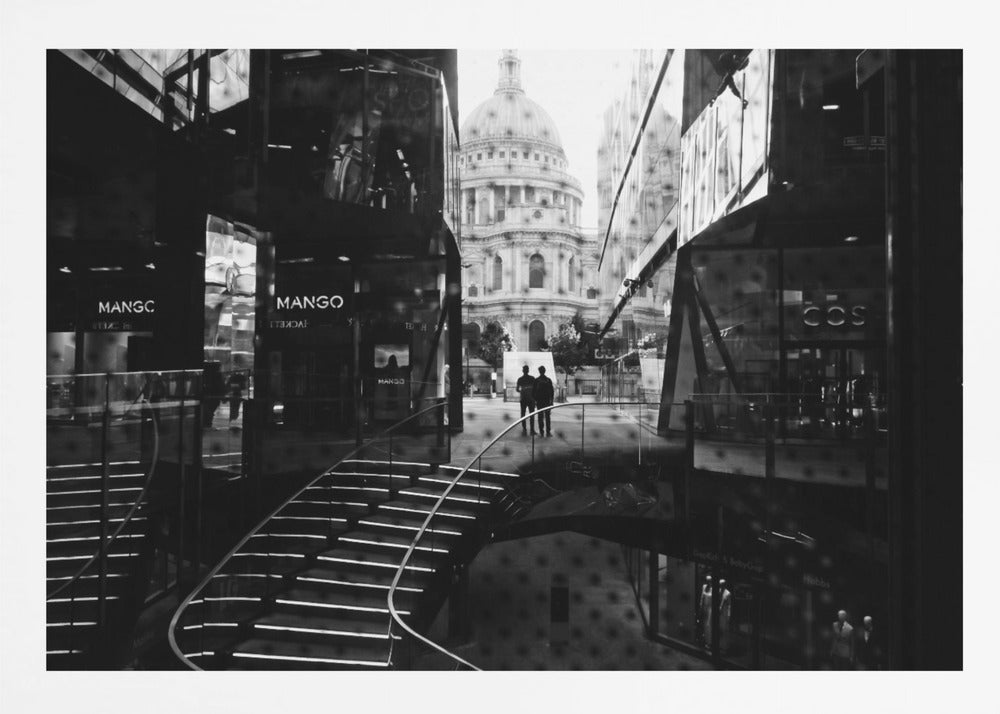 A framed, black and white photograph capturing a layered urban scene. The view, seen through a window with reflections of a curved, lit staircase, shows two people walking towards a large domed cathedral framed by modern glass buildings. Wall Art