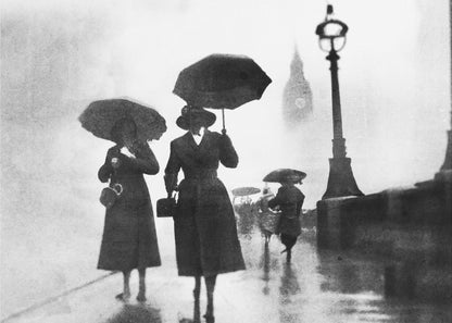 A vintage black and white photograph of people with umbrellas walking on a wet, foggy day in London. The silhouettes of the people are dark against the misty background, where the faint outline of Big Ben and a street lamp are visible. Wall Art