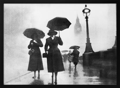 A vintage black and white photograph of people with umbrellas walking on a wet, foggy day in London. The silhouettes of the people are dark against the misty background, where the faint outline of Big Ben and a street lamp are visible. Wall Art
