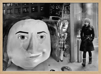 A surreal black and white photograph with a silver frame, featuring a giant, cartoonish head of a historical figure reflected in a window, juxtaposed with a young woman in a winter coat and beanie walking down a city sidewalk. Wall Art
