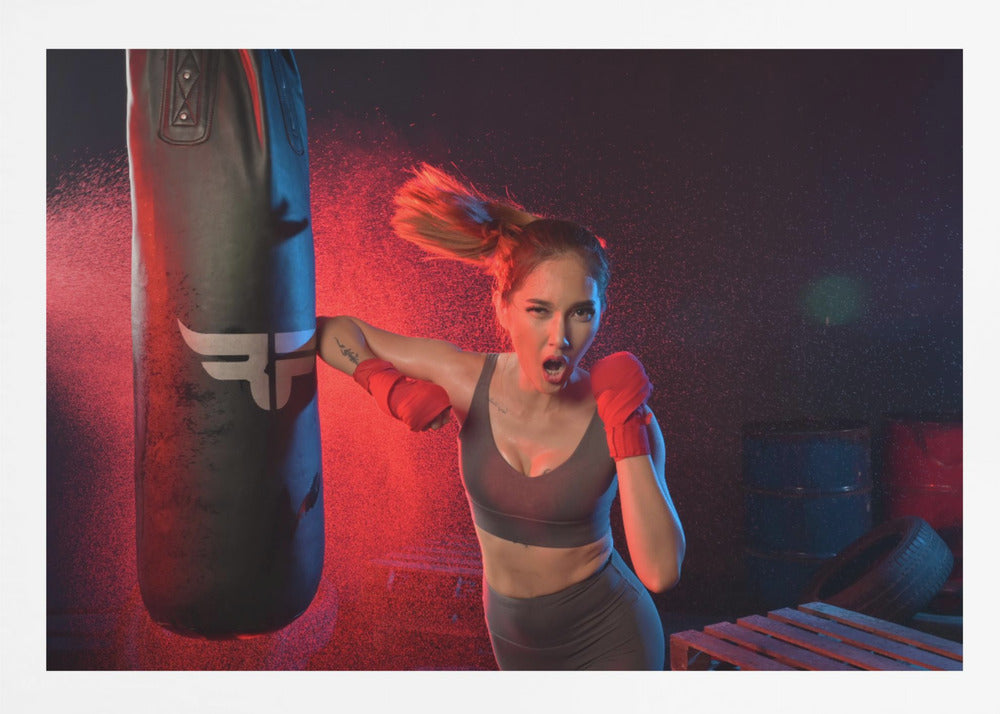 An athletic woman with her hair in a ponytail and red hand wraps fiercely punches a black heavy bag, her mouth open mid-shout. The scene is dramatically lit with red and blue light, and water droplets spray through the air from the impact. Poster