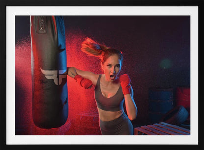An athletic woman with her hair in a ponytail and red hand wraps fiercely punches a black heavy bag, her mouth open mid-shout. The scene is dramatically lit with red and blue light, and water droplets spray through the air from the impact. Poster