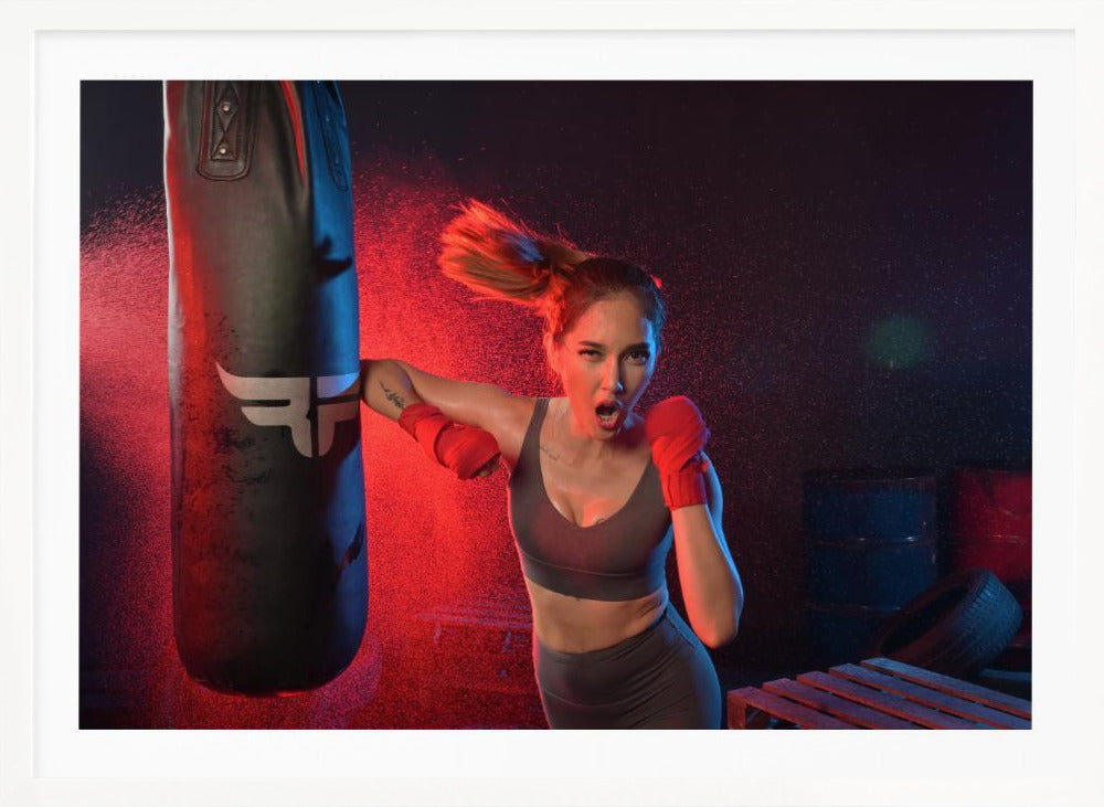 An athletic woman with her hair in a ponytail and red hand wraps fiercely punches a black heavy bag, her mouth open mid-shout. The scene is dramatically lit with red and blue light, and water droplets spray through the air from the impact. Poster