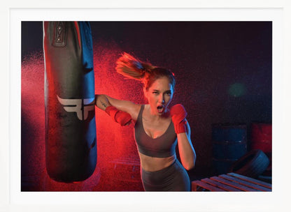 An athletic woman with her hair in a ponytail and red hand wraps fiercely punches a black heavy bag, her mouth open mid-shout. The scene is dramatically lit with red and blue light, and water droplets spray through the air from the impact. Poster