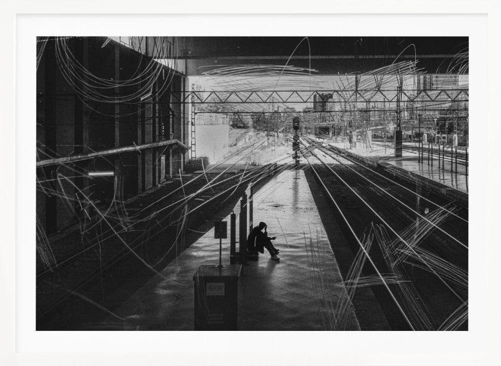 A framed, high-contrast black and white photograph of a person sitting alone on a deserted train platform, with tracks stretching into the distance. The entire scene is overlaid with frenetic white scribbles, creating an abstract and moody effect. Artwork