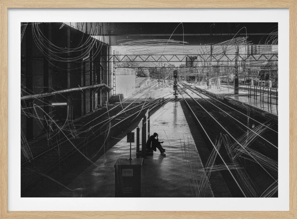 A framed, high-contrast black and white photograph of a person sitting alone on a deserted train platform, with tracks stretching into the distance. The entire scene is overlaid with frenetic white scribbles, creating an abstract and moody effect. Artwork