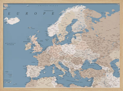 A detailed, framed map of Europe with a muted color palette. The oceans and seas are a soft blue, while the countries are various shades of beige and tan. Text labels for countries, cities, and bodies of water are clearly visible across the map. The map is housed in a simple silver-gray frame. Poster