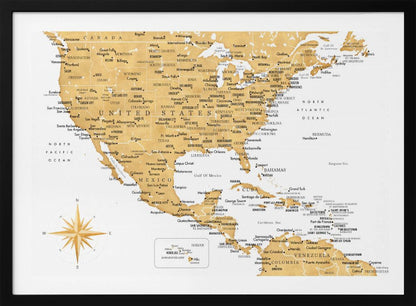 A stylized map of North and Central America and the Caribbean, featuring gold-colored landmasses on a light gray, textured background. Countries, states, and major cities are labeled in black text. A compass rose is shown in the lower-left corner. The entire map is enclosed in a light gray frame. Decor
