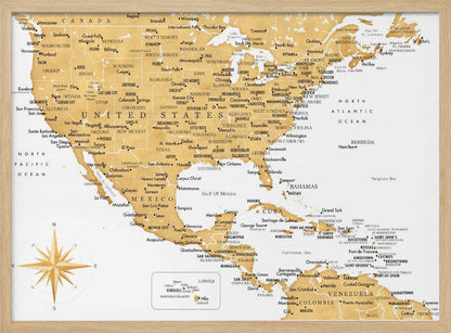 A stylized map of North and Central America and the Caribbean, featuring gold-colored landmasses on a light gray, textured background. Countries, states, and major cities are labeled in black text. A compass rose is shown in the lower-left corner. The entire map is enclosed in a light gray frame. Decor