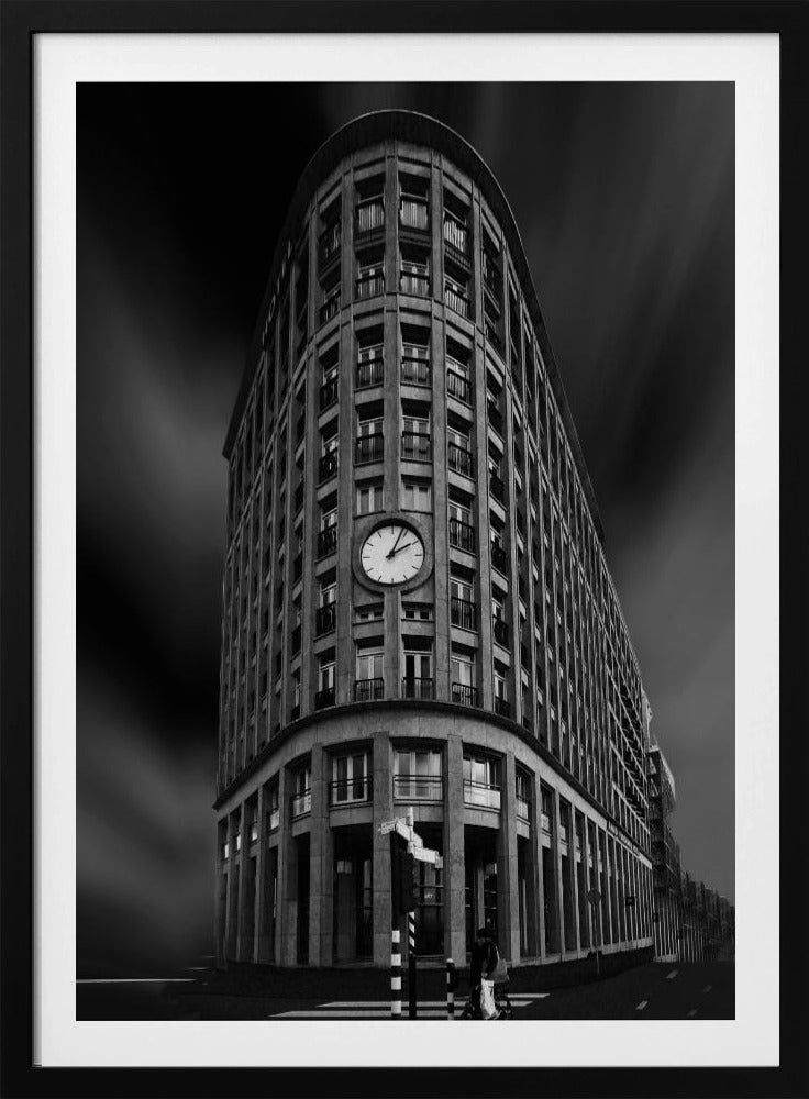 A dramatic low-angle, black and white photograph of a large, curved corner building with a prominent clock on its facade. The sky is dark with a motion blur effect, making the building appear grand and imposing. Artwork