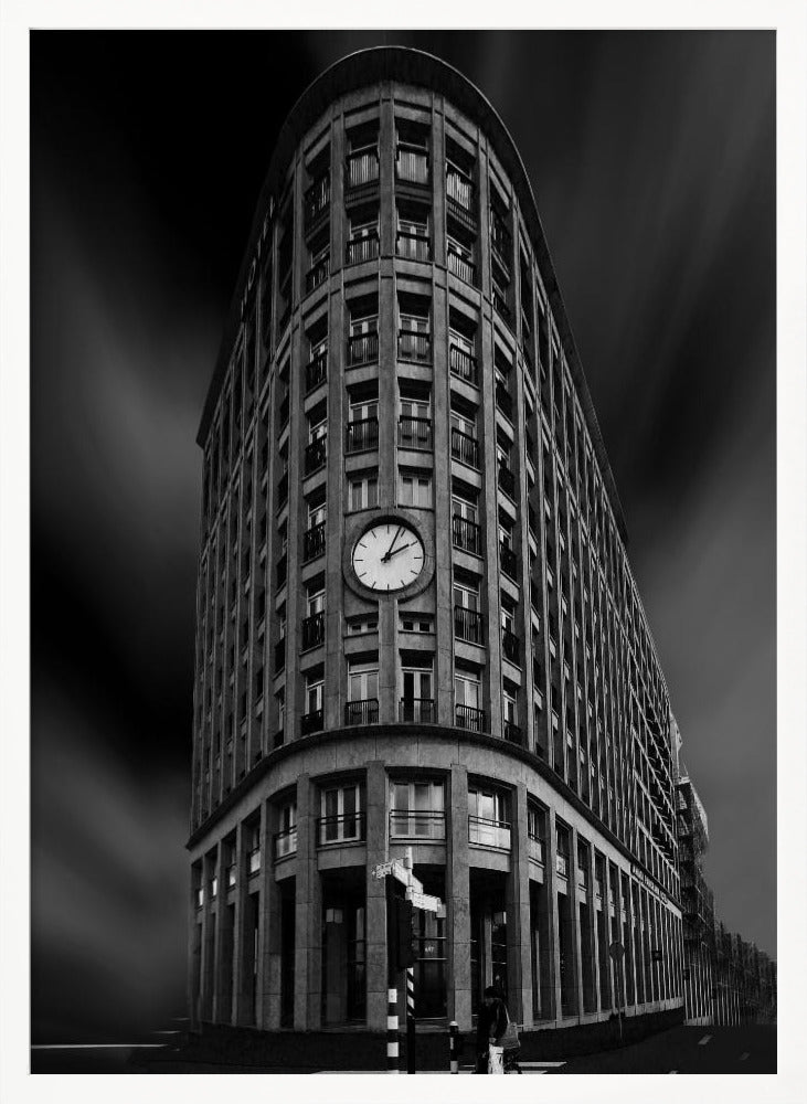 A dramatic low-angle, black and white photograph of a large, curved corner building with a prominent clock on its facade. The sky is dark with a motion blur effect, making the building appear grand and imposing. Artwork