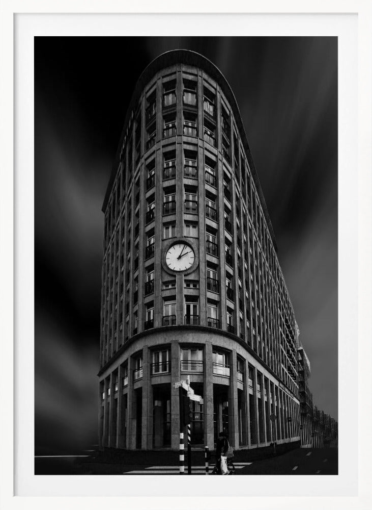 A dramatic low-angle, black and white photograph of a large, curved corner building with a prominent clock on its facade. The sky is dark with a motion blur effect, making the building appear grand and imposing. Artwork