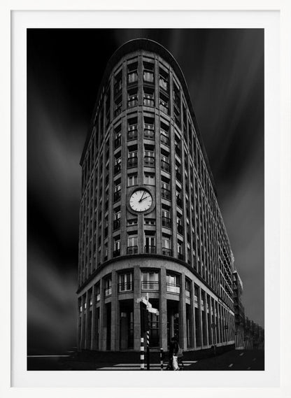 A dramatic low-angle, black and white photograph of a large, curved corner building with a prominent clock on its facade. The sky is dark with a motion blur effect, making the building appear grand and imposing. Artwork