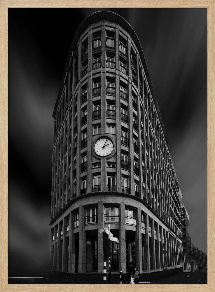 A dramatic low-angle, black and white photograph of a large, curved corner building with a prominent clock on its facade. The sky is dark with a motion blur effect, making the building appear grand and imposing. Artwork