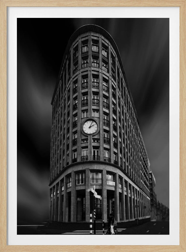 A dramatic low-angle, black and white photograph of a large, curved corner building with a prominent clock on its facade. The sky is dark with a motion blur effect, making the building appear grand and imposing. Artwork