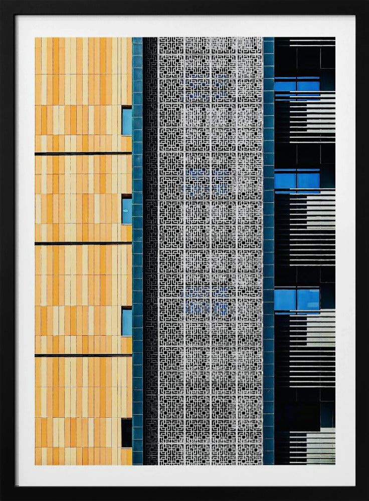 A vertical abstract architectural photograph showcasing the facade of a modern building, featuring a contrast of textures and colors: warm yellow vertical tiles on the left, an intricate white geometric screen in the center, and a dark section with vibrant blue windows on the right. Print
