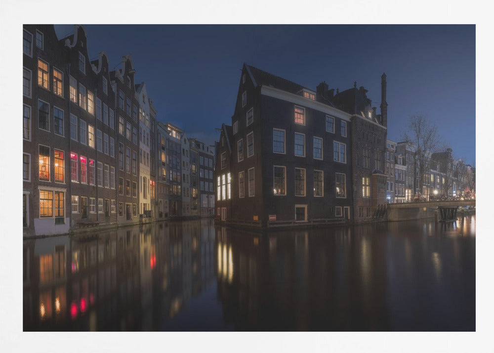 A framed photograph capturing a serene night view of an Amsterdam canal. Traditional Dutch houses with lit windows line the calm water, casting warm reflections under a deep blue twilight sky. Wall Art