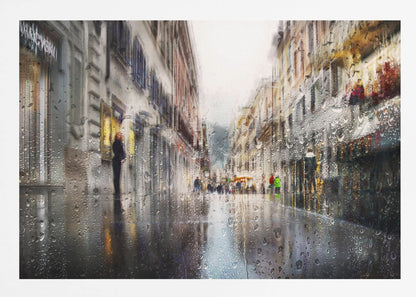 An impressionistic painting of a city street on a rainy day, viewed as if through a window covered in water droplets. The scene is blurred and atmospheric, with the wet pavement reflecting the muted colors of the buildings and distant figures. The artwork is presented in a silver frame. Decor