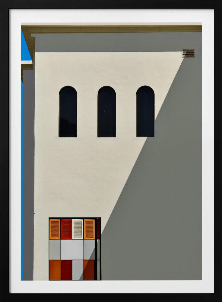 A minimalist photograph of a cream-colored building facade with a sharp diagonal shadow. Three black arched windows are arranged horizontally, and below them, a colorful grid of red, orange, and white panels. A vibrant blue vertical stripe is visible on the far left edge. Wall Art