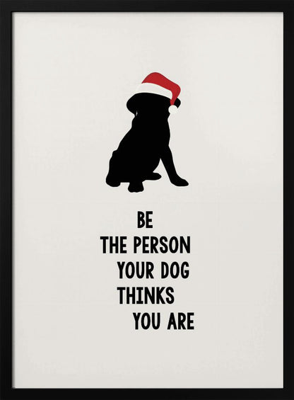 A framed art print featuring a black silhouette of a dog wearing a red Santa hat on an off-white background. Below the dog is the motivational quote, 'BE THE PERSON YOUR DOG THINKS YOU ARE' in black block letters. Decor