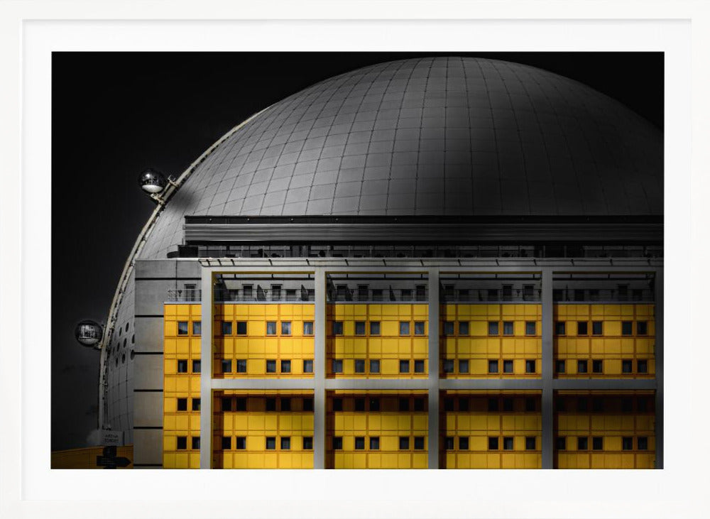 A framed architectural photograph with selective color, featuring a bright yellow building in the foreground against a monochrome background of a large grey dome structure under a black sky. Wall Art