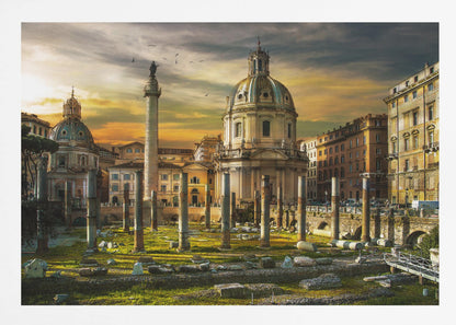 A framed photograph of Trajan's Forum in Rome, Italy, during a dramatic sunset. The foreground is filled with ancient stone columns and ruins on a grassy field, leading to the prominent Trajan's Column and the domed Church of the Most Holy Name of Mary against a golden and dark cloudy sky. Wall Art