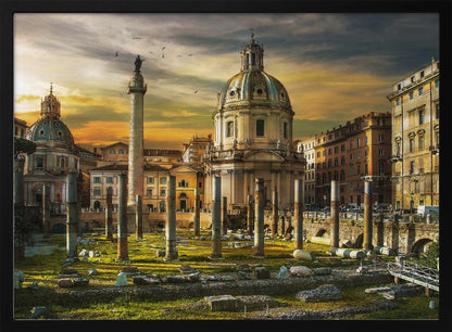 A framed photograph of Trajan's Forum in Rome, Italy, during a dramatic sunset. The foreground is filled with ancient stone columns and ruins on a grassy field, leading to the prominent Trajan's Column and the domed Church of the Most Holy Name of Mary against a golden and dark cloudy sky. Wall Art