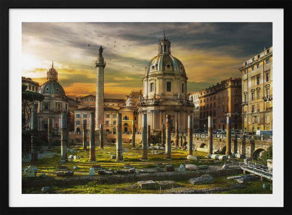 A framed photograph of Trajan's Forum in Rome, Italy, during a dramatic sunset. The foreground is filled with ancient stone columns and ruins on a grassy field, leading to the prominent Trajan's Column and the domed Church of the Most Holy Name of Mary against a golden and dark cloudy sky. Wall Art