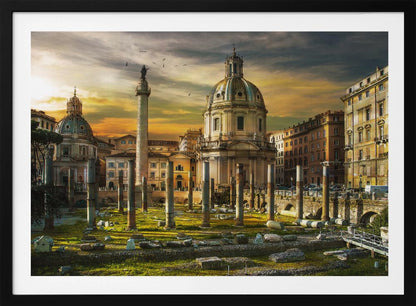 A framed photograph of Trajan's Forum in Rome, Italy, during a dramatic sunset. The foreground is filled with ancient stone columns and ruins on a grassy field, leading to the prominent Trajan's Column and the domed Church of the Most Holy Name of Mary against a golden and dark cloudy sky. Wall Art