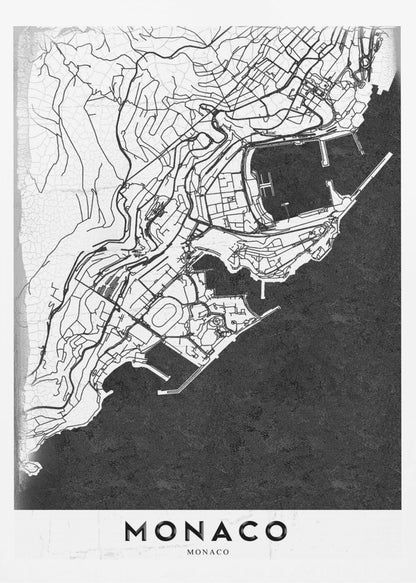 A modern black and white map of Monaco, presented as a framed poster. The map details the city's streets and coastline in black lines on a white background, while the sea is depicted in a solid, textured black. The title 'MONACO' is at the bottom in a bold, white band. Poster