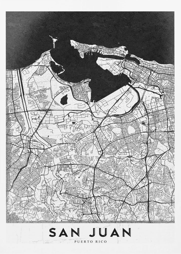 A minimalist black and white map of San Juan, Puerto Rico, shown as a framed poster. The land is depicted in white with intricate black lines for roads and streets, while the surrounding water is a solid, textured black. A white banner at the bottom features the text 'SAN JUAN' in a bold, black, sans-serif font. Artwork