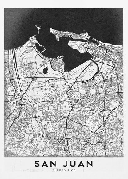 A minimalist black and white map of San Juan, Puerto Rico, shown as a framed poster. The land is depicted in white with intricate black lines for roads and streets, while the surrounding water is a solid, textured black. A white banner at the bottom features the text 'SAN JUAN' in a bold, black, sans-serif font. Artwork