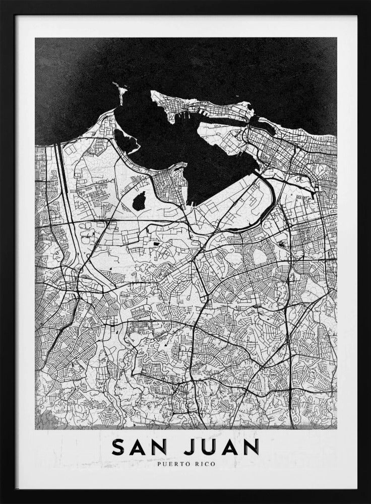 A minimalist black and white map of San Juan, Puerto Rico, shown as a framed poster. The land is depicted in white with intricate black lines for roads and streets, while the surrounding water is a solid, textured black. A white banner at the bottom features the text 'SAN JUAN' in a bold, black, sans-serif font. Artwork