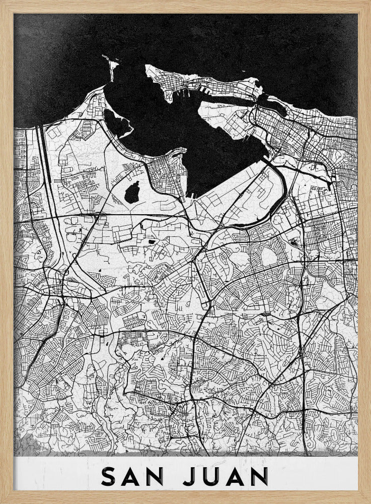 A minimalist black and white map of San Juan, Puerto Rico, shown as a framed poster. The land is depicted in white with intricate black lines for roads and streets, while the surrounding water is a solid, textured black. A white banner at the bottom features the text 'SAN JUAN' in a bold, black, sans-serif font. Artwork